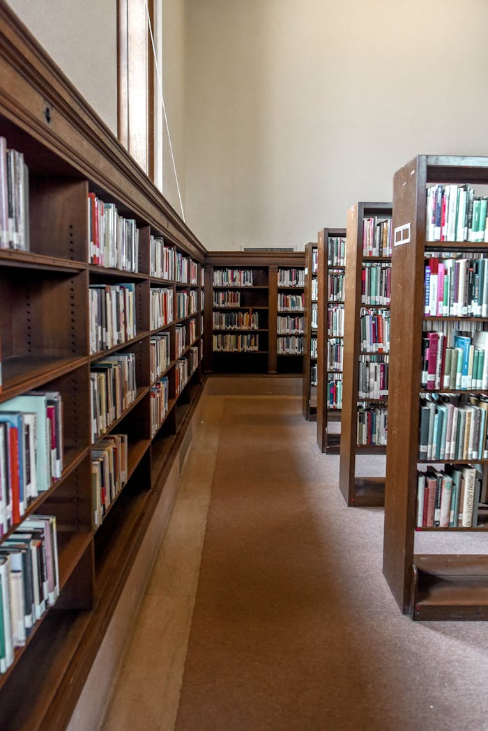 Empty library aisle lined with wooden bookshelves filled with books.